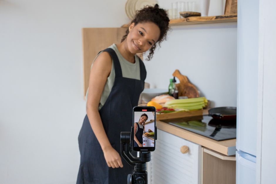A creator filming a video at home on a smartphone mounted to a stabilizer