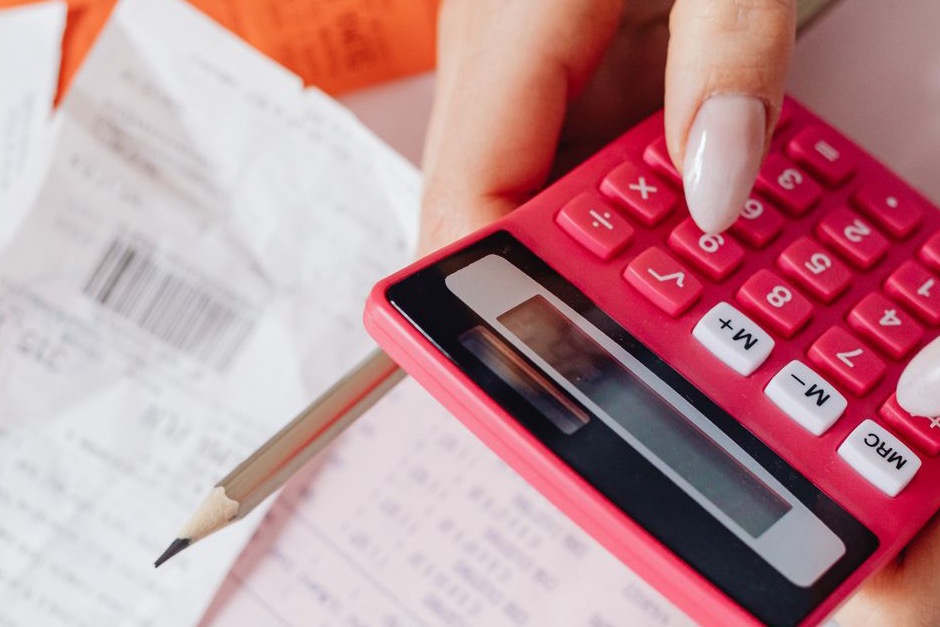 Hands using a calculator on a desk covered with receipts and documents
