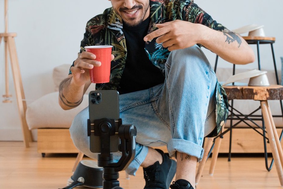 A man filming a vlog in a living room with a smartphone mounted on a tripod